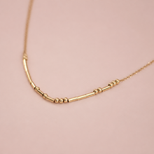 Load image into Gallery viewer, A delicate gold chain necklace featuring a central bar with small bead accents.
